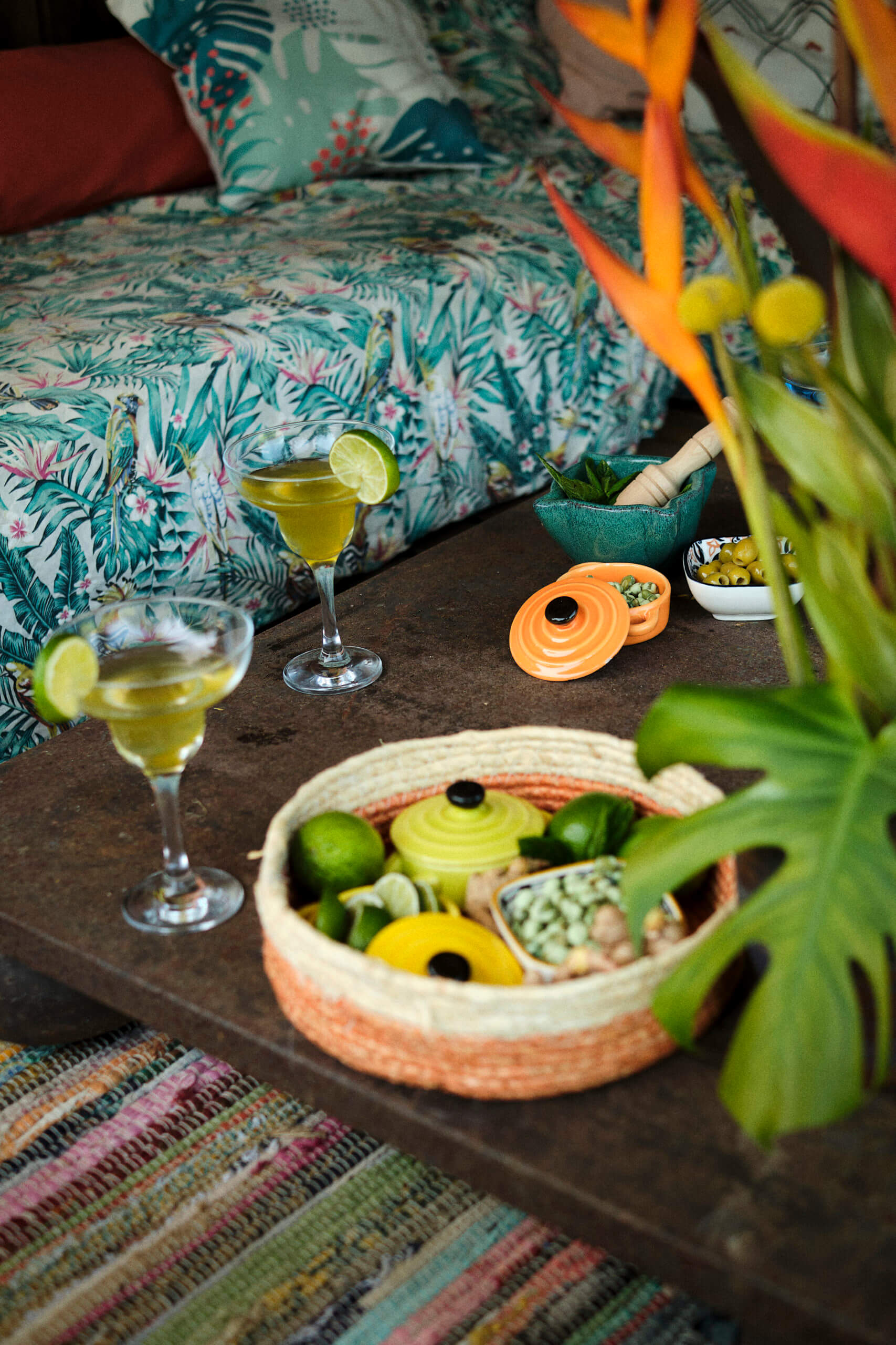 Salon de jardin avec table dressée pour la bamboche : cocktails, citrons verts, pots colorés, cacahuètes au wasabi, etc.